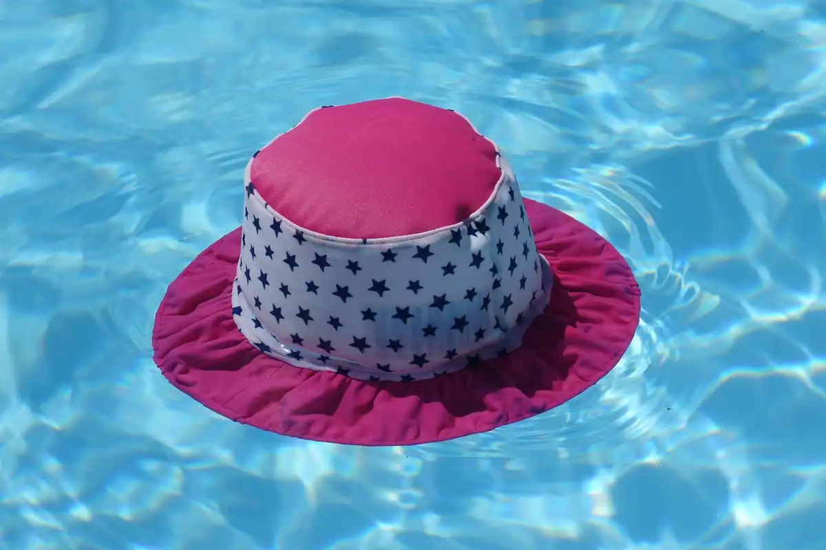 Pălărie de soare colorată plutind pe apa albastră și limpede a unei piscine
