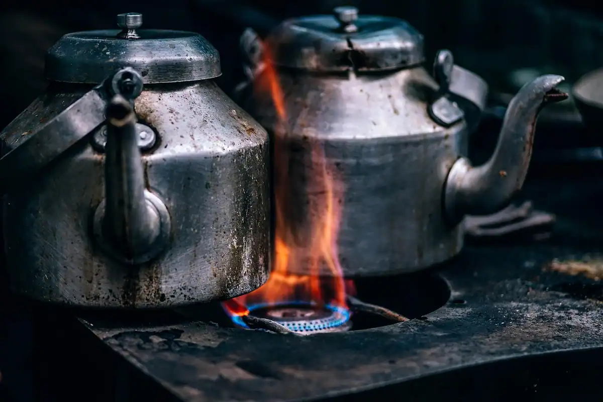 Două ceainice vechi încălzite pe flacăra albastră a unui aragaz pe gaz